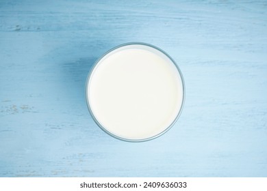 Glass with milk on a wooden light blue background. Top view. - Powered by Shutterstock