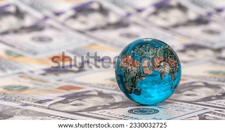 Glass miniature globe against the background of 100 American dollar bills