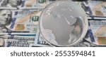 Glass miniature globe on a background of 100 dollar bills. World economy and investment