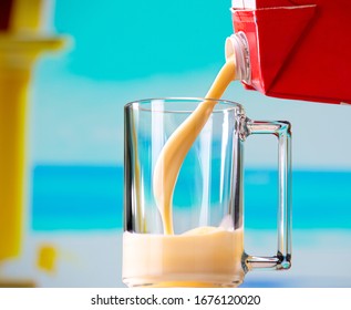 Glass Mug And Banana Milk With Ice Cream Pouring From Milk Carton