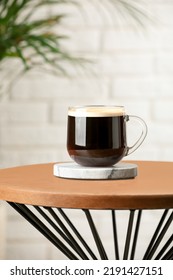 Glass Mug Of Coffee With Stylish Stone Cup Coaster On Wooden Table In Room