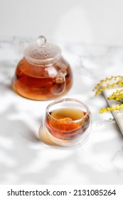 A Glass Mug Or Cup With Herbal Tea And A Teapot In Sunny Day. Spring, Summer.