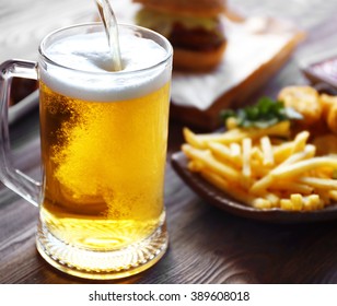 Glass Mug Of Draft Light Beer With French Fries On Dark Wooden Table, Close Up