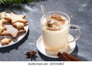 Glass mug with traditional Christmas drink eggnog with cinnamon and heart shape cookies on grey. - Powered by Shutterstock