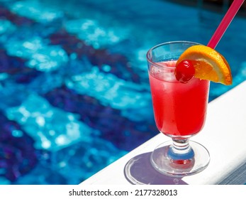 Glass Of Non Alcoholic Pink Panther Cocktail On Pool Nosing At Tropical Resort. Horizontal, Cocktail On Right Side. Healthy Cold Drink. Pool Cocktail Party. Copy Space