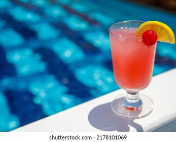 Glass Of Non Alcoholic Pink Strawberry Lemonade Cocktail On Pool Nosing At Tropical Resort. Horizontal, Cocktail On Right Side. Healthy Fresh Cold Drink. Pool Cocktail Party. Copy Space