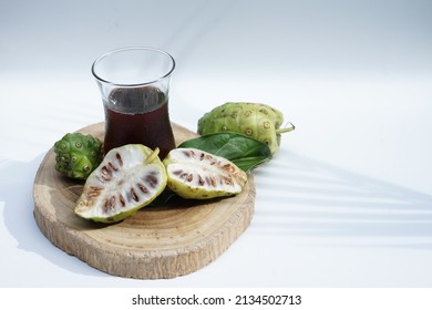 a glass of noni juice extracted and sliced on white background,selective focus