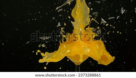 Glass of Orange Exploding against Black Background
