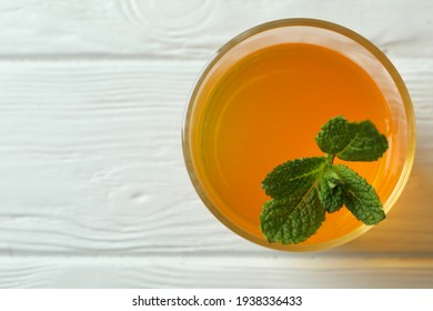 Glass of orange jelly with mint on white wooden table