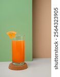 a glass of orange juice with a colored background.