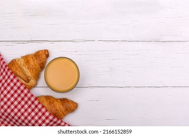 Glass Of Orange Juice And Croissants Under Red Gingham Napkin On White Wooden Breakfast Table.  Flat Lay With Copy Space 