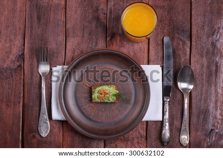 A glass of orange juice, a plate of canapes and cutlery. Canapes with paste of avocado. A tiny portion, anorexia. Eating disorders, poor nutrition. A strict diet. Plate and cutlery