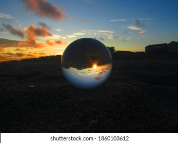 Glass Orb On A Beach At Sunset