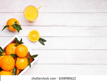 Glass of organic fresh orange smoothie juice with raw oranges on light  wooden background in white wooden box.Top view. - Powered by Shutterstock