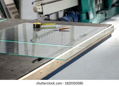 The glass pane and the cutting tools lying on a professional glass table