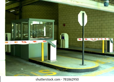 Glass Pay Booth At The Entrance And Exit Of A Parking Garage In Front Of A Stop Sign In Between Toll Arms