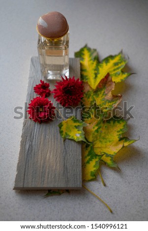 
glass perfume bottle with autumn leaves and chrysanthemum flowers