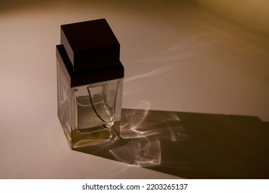 Glass Perfume Bottle Container With A Long Shadow On Dark Background