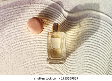 Glass Perfume Bottle On A Sandy Textured Background With Long Shadow. Summer Vocation Fragrance Concept