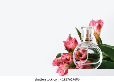 Glass perfume bottle on white podium. Floral arrangement. Minimal mockup style, soft focus, low angle - Powered by Shutterstock