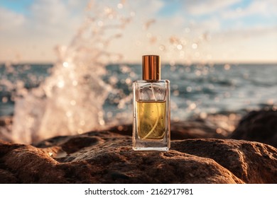 A glass perfume bottle stands on the stones, close-up. In the background is the ocean, the horizon line and the sea surf. The concept of selective perfumery. - Shutterstock ID 2162917981