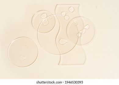 Glass petri dish with transparent pure serum for skin care on beige background, top view. Concept laboratory tests and research