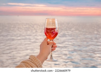 a glass of pink cider on the background of the water surface and the sunset sky - Powered by Shutterstock