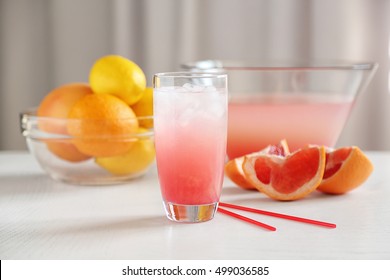 Glass Of Pink Lemonade And Grapefruits On White Table