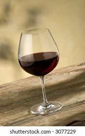 Glass Of Pinot Noir Wine On Rustic Wooden Table, Warm Colored Background,nice Red Glow In Glass