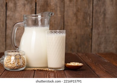 Glass Pitcher Of Milk On Old Wooden Table