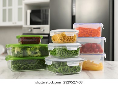 Glass and plastic containers with different fresh products on white marble table in kitchen. Food storage
