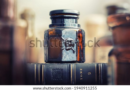 Glass poison bottle with skull and bones. Danger sign, symbol of death. Concept background on poison poisoning, pharmaceutical, chemistry, medical, old science topic.