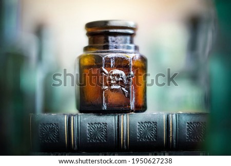 Glass poison bottle with skull and bones. Danger sign, symbol of death. Concept background on poison poisoning, pharmaceutical, chemistry, medical, old science topic.