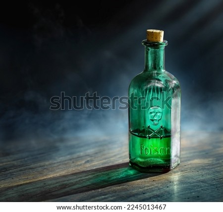 Glass poison bottle with skull and bones. Danger sign, symbol of death. Concept background on poison poisoning, chemistry, pharmacy, medical topic. Poison, venom, toxin, toxic, bane, virus background.