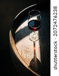 Glass of Porto wine on a wooden oak barrel with long shadow in moody atmosphere 