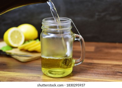 A Glass Is Poured With Hot Water And A Tea Bag For Peppermint Tea Hangs Inside. Fresh Peppermint Tea Is Boiled Up, Suitable For The Winter And Flu Season