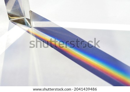 Glass prism for optical physics experiments in education, splitting the light into reflection beams in the spectrum of rainbow colors, bright background, copy space, selected focus