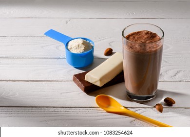 Glass Of Protein Shake With Energy Bars On White Wooden Table