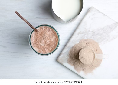 Glass With Protein Shake, Jug Of Milk And Powder On White Wooden Table, Top View