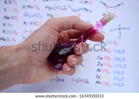 Glass pycnometer for measuring the density of liquid substances, with a purple aqueous solution of potassium permanganate, in the hand.