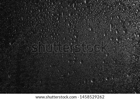 Glass with rain drops against dark background