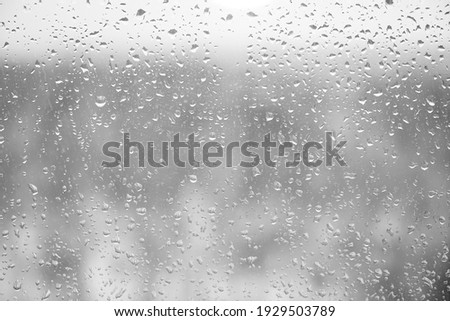 Glass with rain drops against gray background. 