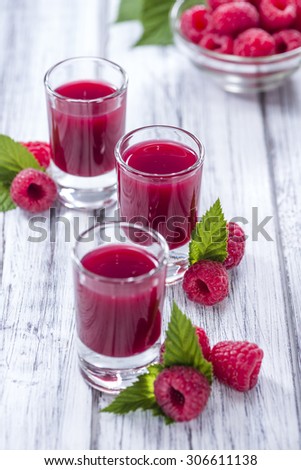 Glass with Raspberry Liqueur and fresh fruits on wooden background
