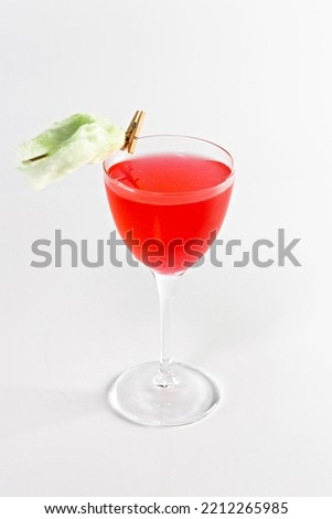 Glass with red berries cocktail on a white background. The drinks is decorated with flower.