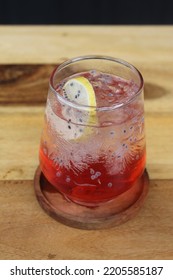 A Glass Of Red Mocktail With Basil And Lemon As Garnish