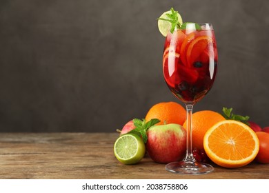 Glass of Red Sangria and fruits on wooden table, space for text