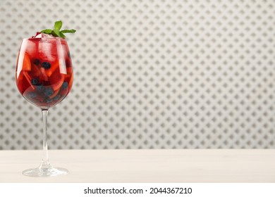 Glass of Red Sangria with fruits on white wooden table, space for text