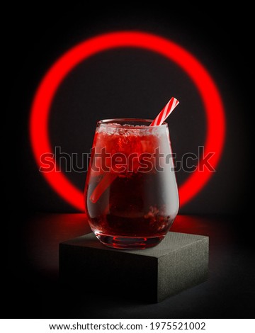 glass of red soft drink on black background with red neon circle