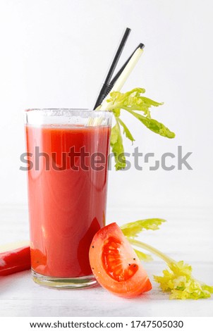 glass of red tomato juice with fresh tomatoes, chili, celery, on a white