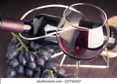 Glass of red wine with bottle and grapes. Winery background toned image